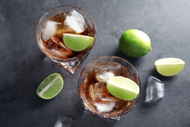 Photo of Glasses of refreshing drink with ice cubes and lime on table, top view