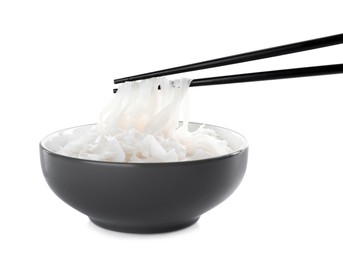 Photo of Chopsticks with cooked rice noodles over bowl isolated on white