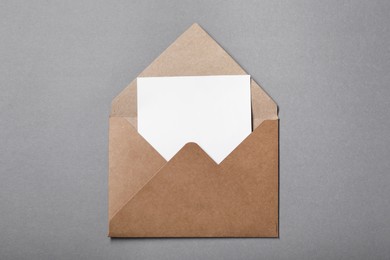 Photo of Blank sheet of paper in open letter envelope on grey background, top view