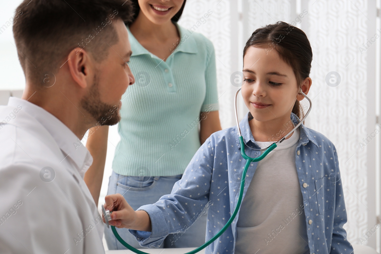 Photo of Mother and daughter visiting pediatrician in hospital. Little girl playing with doctor