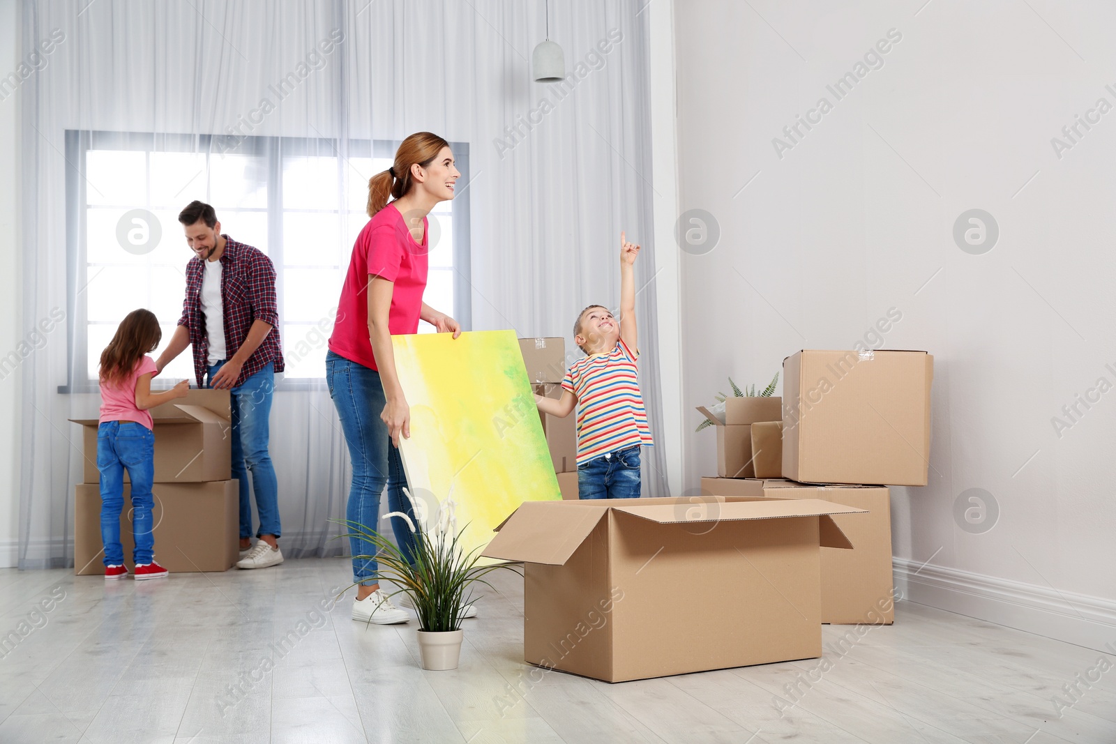 Photo of Happy family unpacking boxes in their new house. Moving day