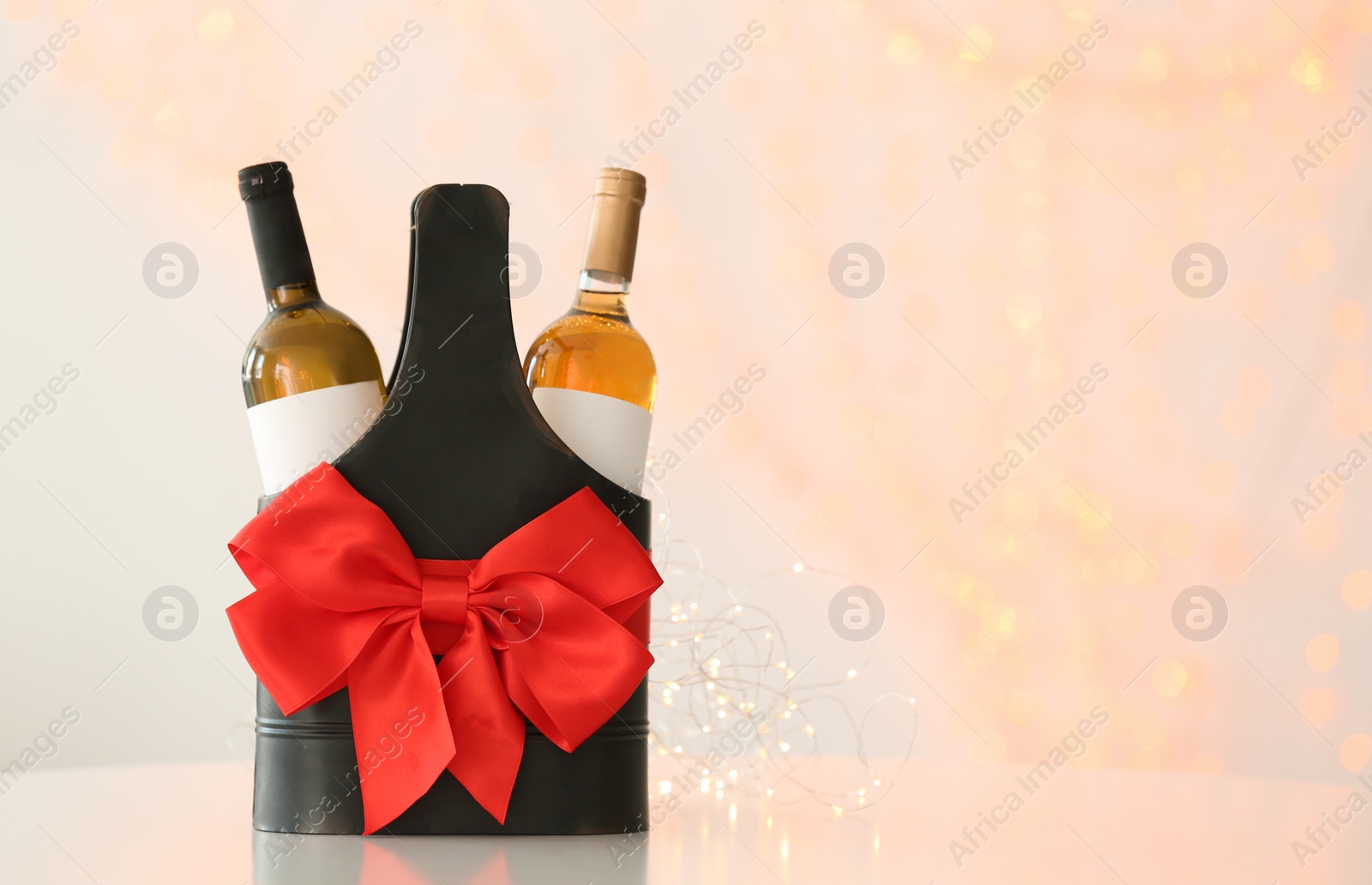 Photo of Festive package with bottles of wine against blurred background. Space for text