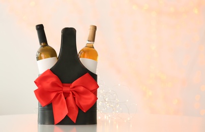 Photo of Festive package with bottles of wine against blurred background. Space for text