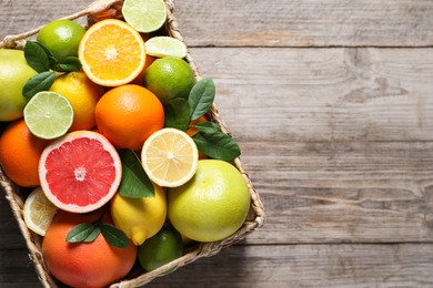 Different cut and whole citrus fruits on wooden table, top view. Space for text