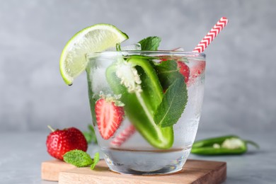 Photo of Spicy cocktail with jalapeno, strawberry, lime and mint on light grey table, closeup