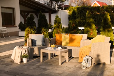 Beautiful rattan garden furniture, soft pillows and different decor elements in backyard
