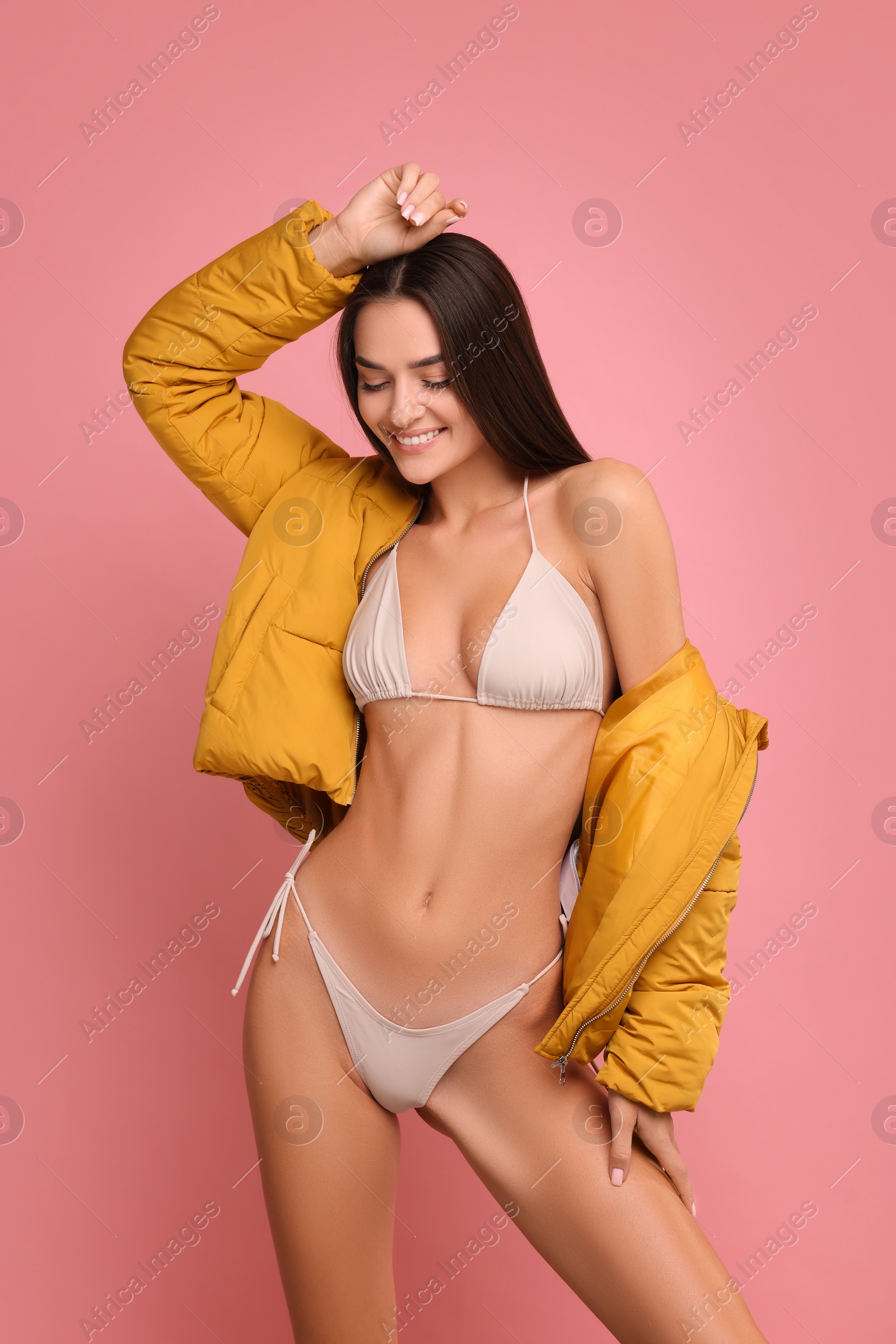 Photo of Young woman in stylish bikini and jacket on pink background