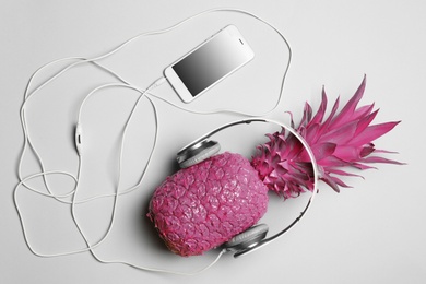 Photo of Pineapple with headphones and smartphone on grey background, top view