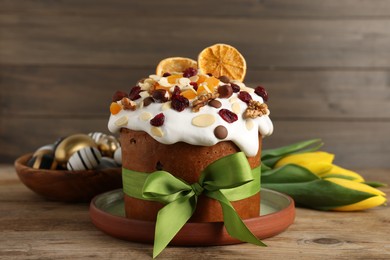 Photo of Tasty Easter cake with dried fruits, flowers and decorated eggs on wooden table
