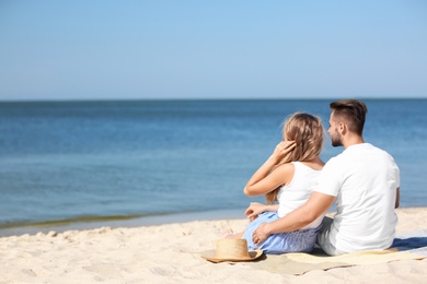 Photo of Happy young couple sitting together at beach on sunny day