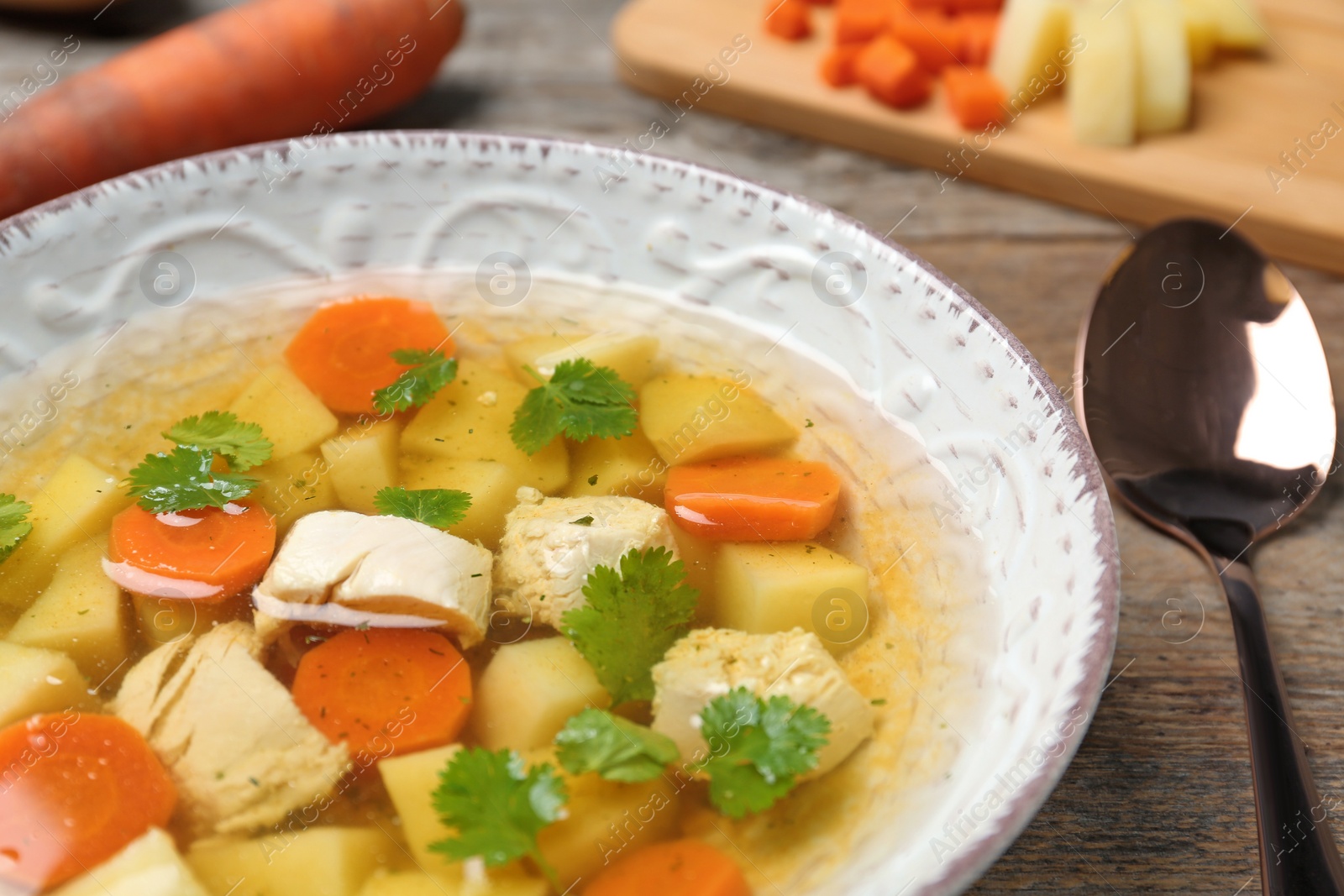 Photo of Dish with fresh homemade chicken soup on wooden table, closeup