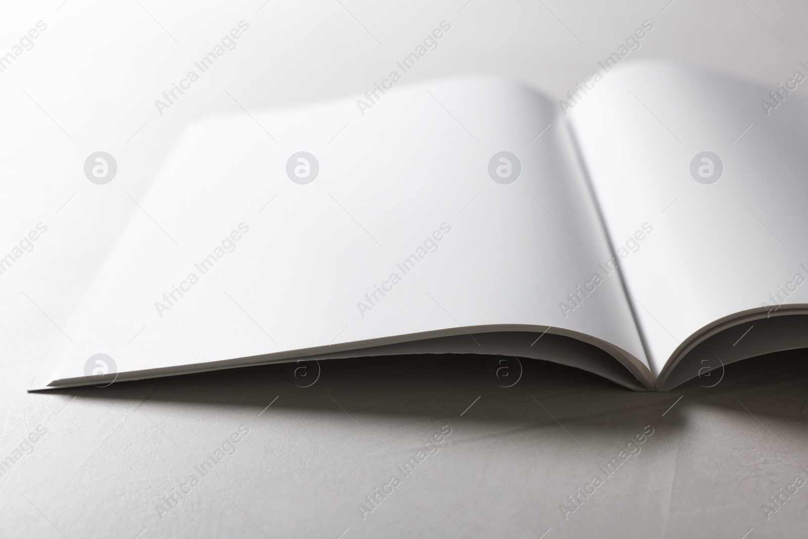 Photo of Open notebook with blank pages on grey textured table, closeup. Mockup for design