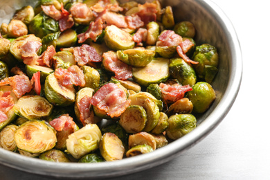 Roasted Brussels sprouts with bacon on white wooden table, closeup