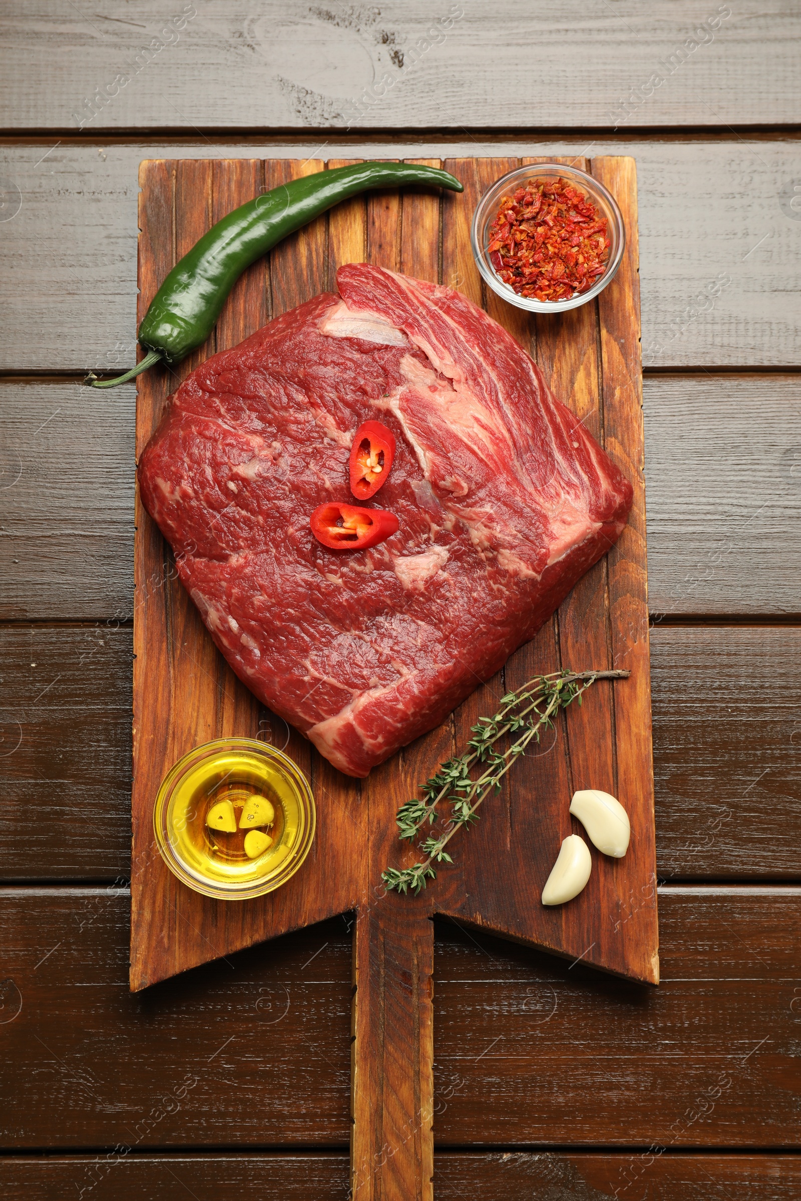 Photo of Fresh raw beef cut, spices and oil on wooden table, top view