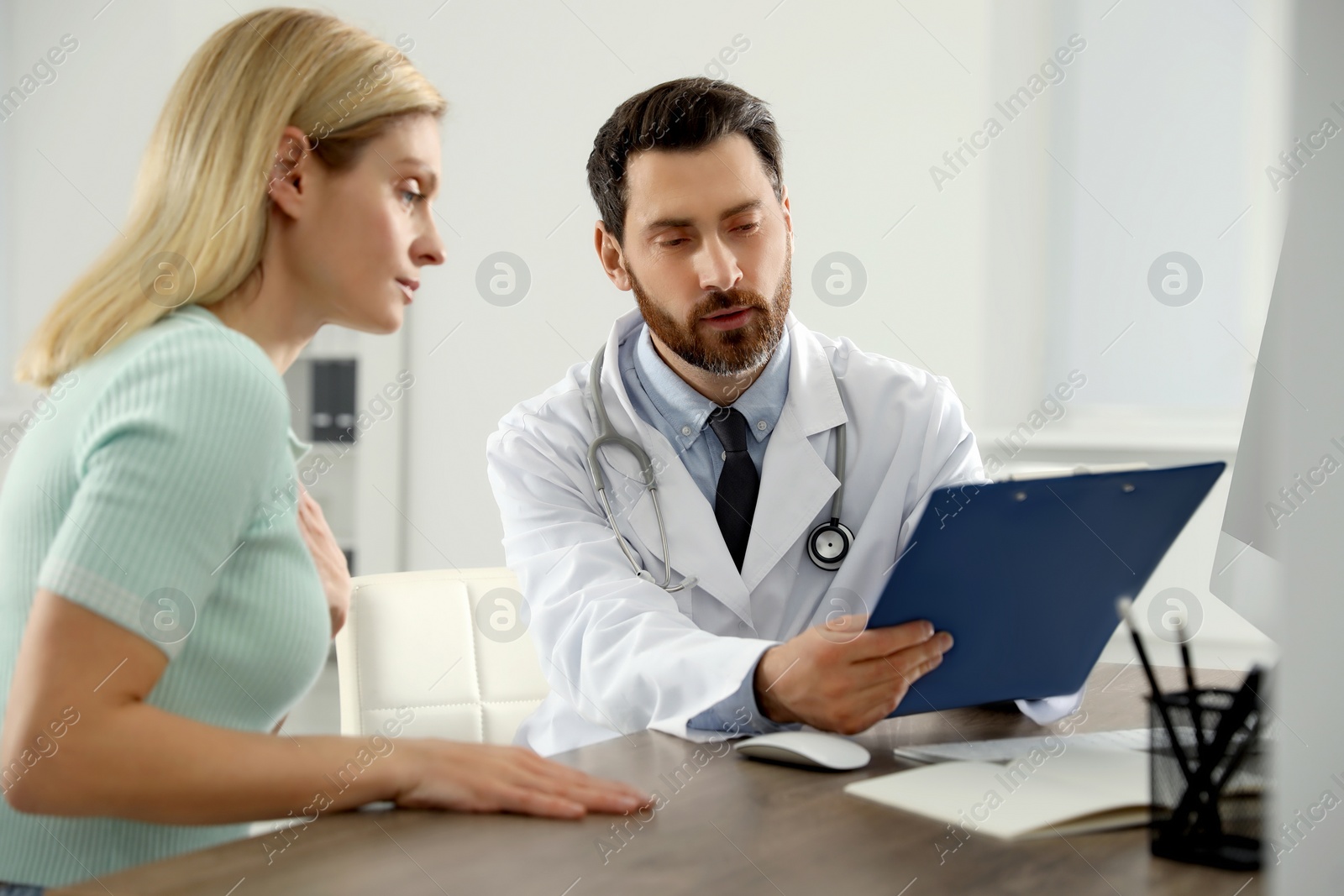 Photo of Doctor consulting patient at wooden table in clinic