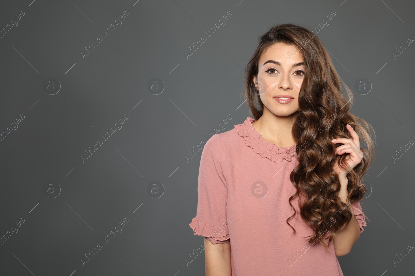 Photo of Beautiful woman with shiny wavy hair on grey background. Space for text