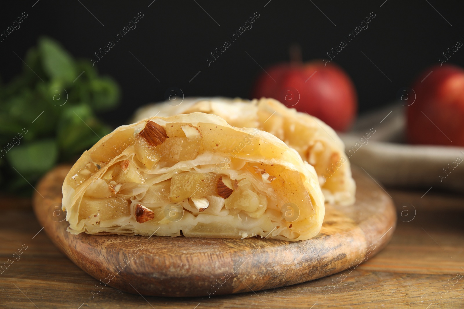 Photo of Delicious apple strudel with almonds on wooden table, closeup