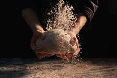 Making bread. Woman kneading dough at table on dark background, closeup