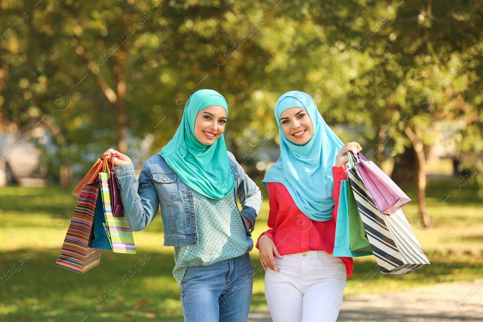 Photo of Muslim women with shopping bags walking in park