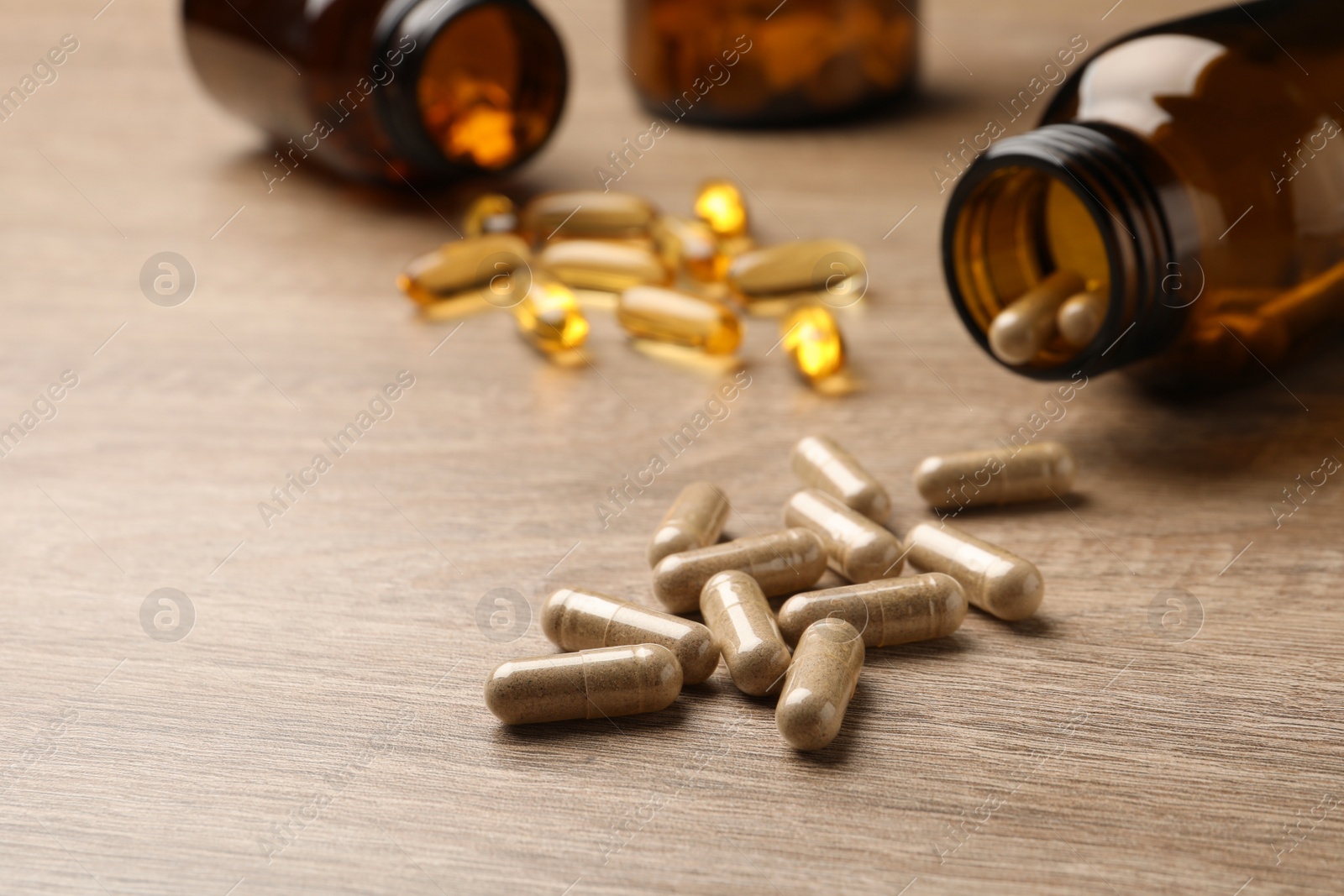 Photo of Overturned bottle with dietary supplement capsules on wooden table, closeup. Space for text
