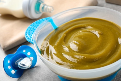 Photo of Bowl of healthy baby food on grey table, closeup