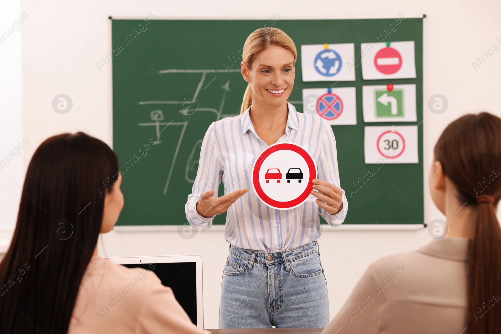 Photo of Teacher showing No Overtaking road sign during lesson in driving school