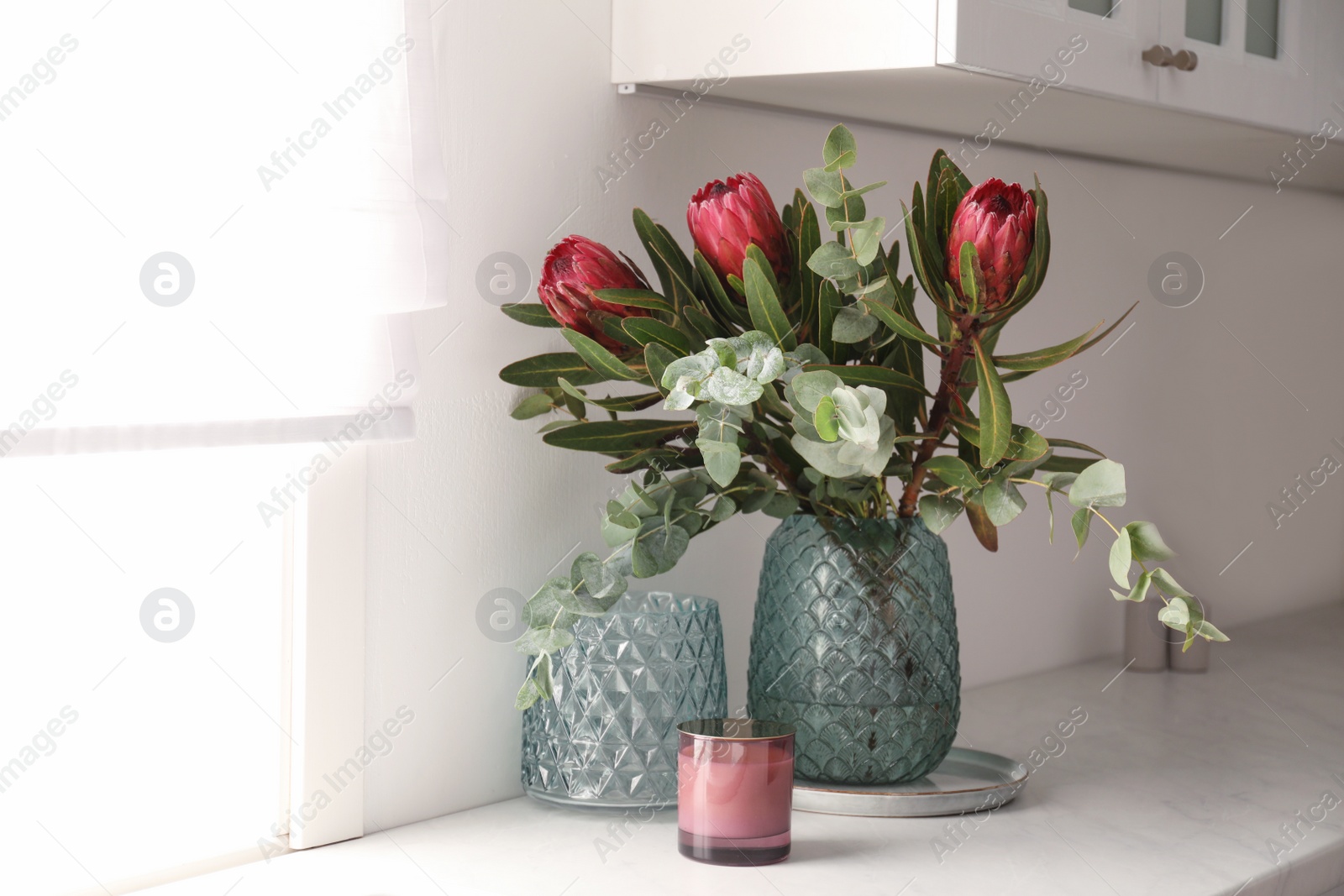 Photo of Bouquet with beautiful protea flowers on countertop in kitchen. Interior design