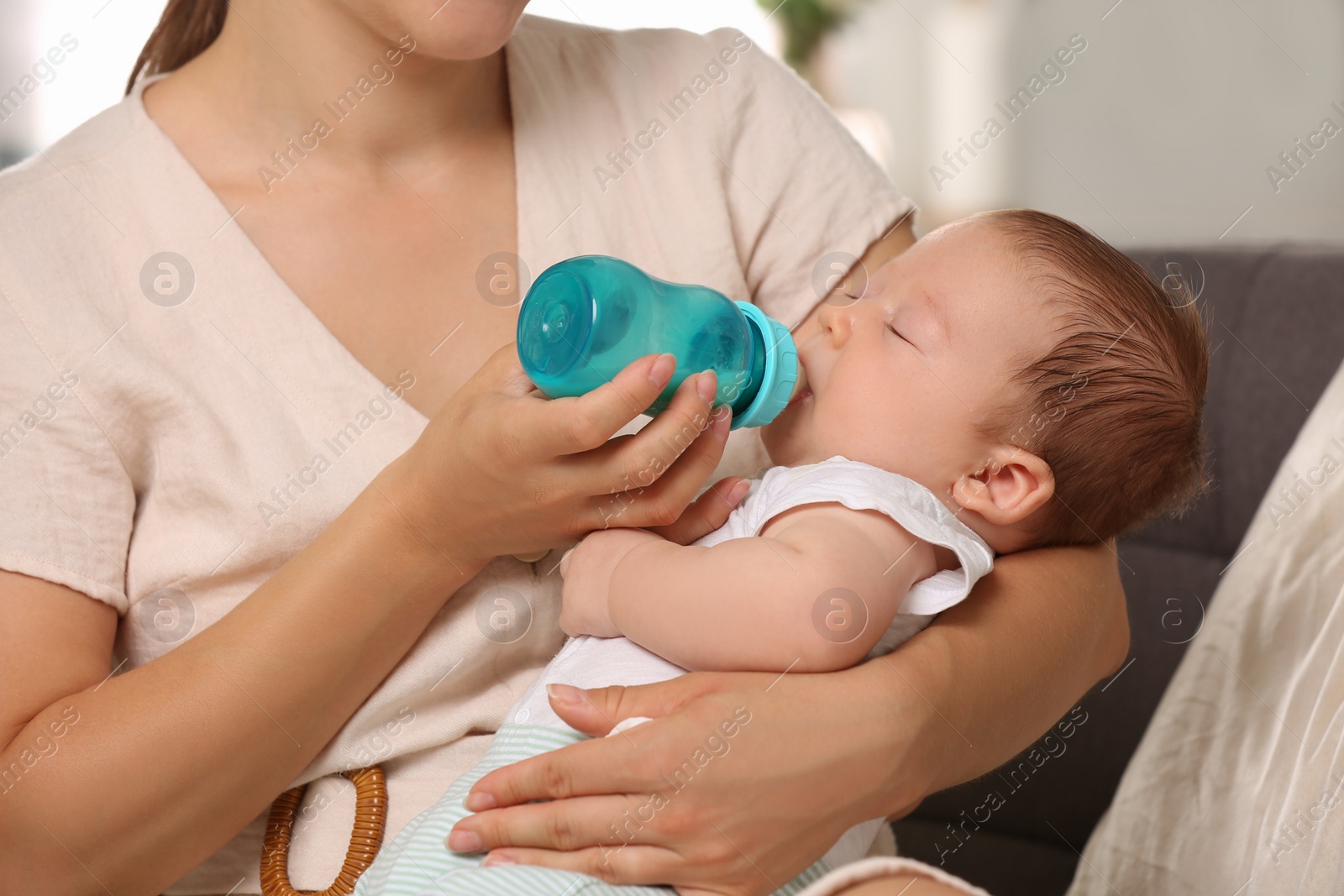 Photo of Mother feeding her cute child with infant formula indoors