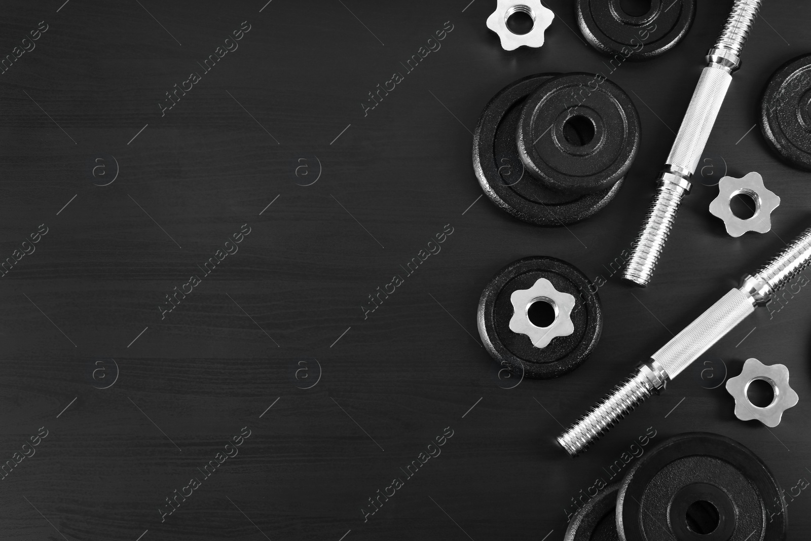 Photo of Flat lay composition with dumbbell parts and space for text on dark wooden background