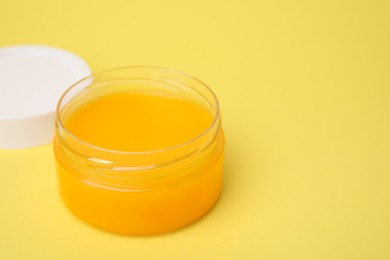 Photo of Open jar of petrolatum on yellow background. Space for text