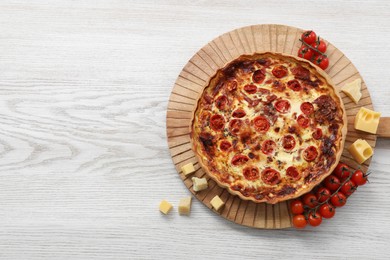 Delicious homemade prosciutto quiche and ingredients on white wooden table, flat lay. Space for text