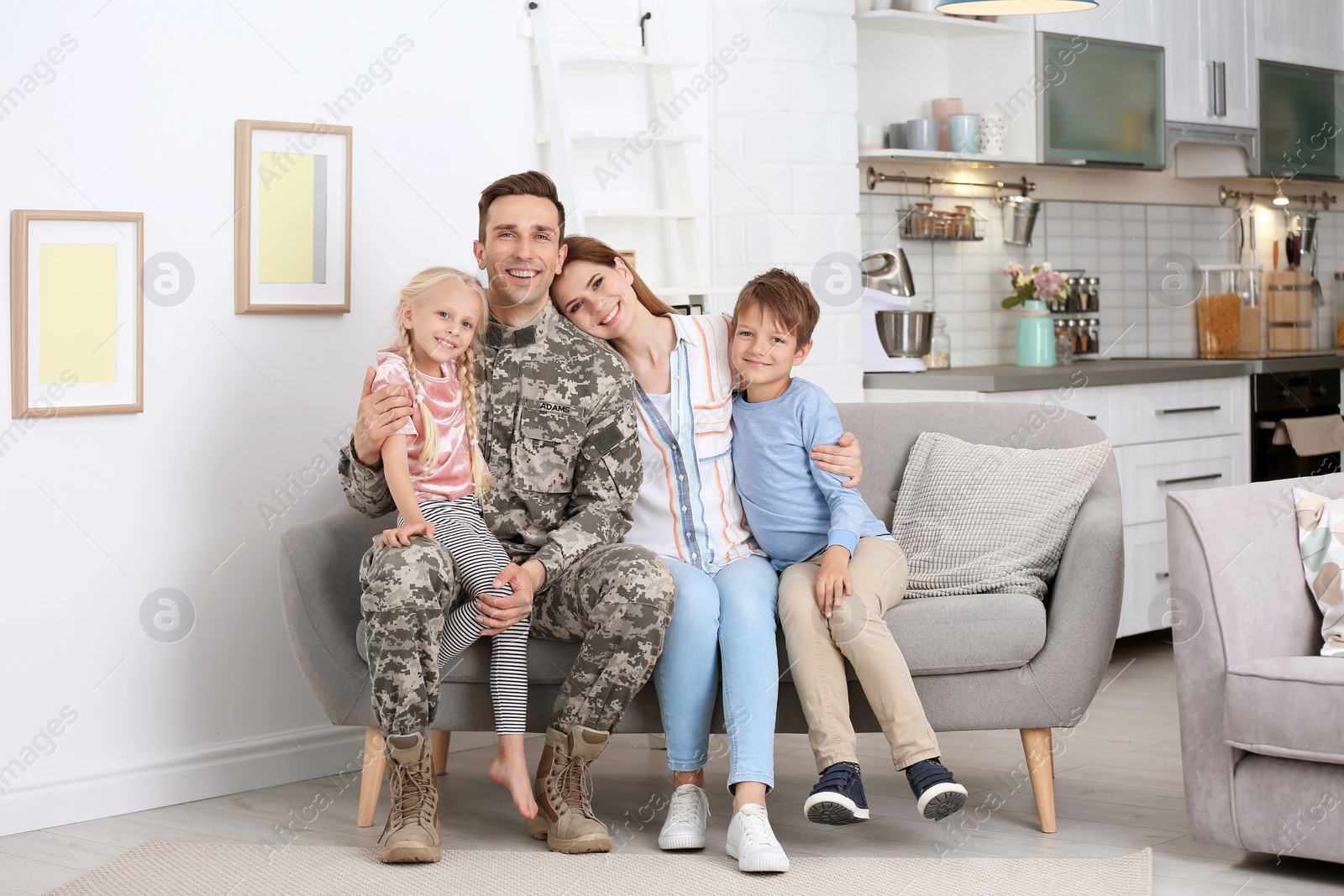 Photo of Man in military uniform with his family on sofa at home