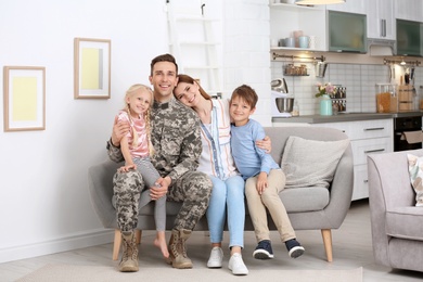 Photo of Man in military uniform with his family on sofa at home