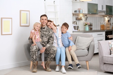 Man in military uniform with his family on sofa at home