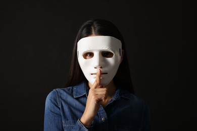 Multiple personality concept. Woman in mask on black background