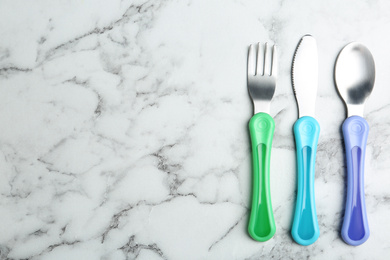 Photo of Set of small cutlery on white marble table, flat lay with space for text. Serving baby food