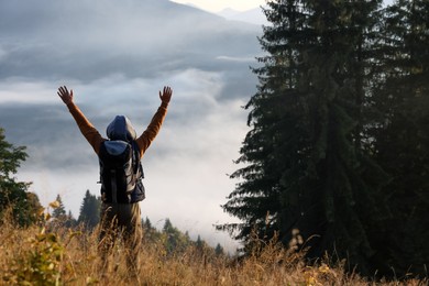 Photo of Tourist with backpack in nature on sunny day, back view. Space for text