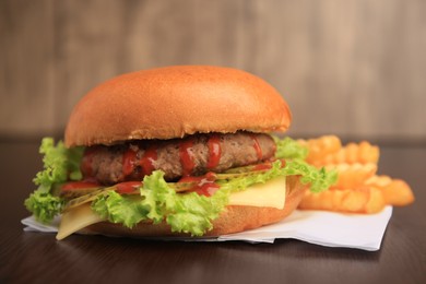 Tasty burger with french fries on wooden table, closeup