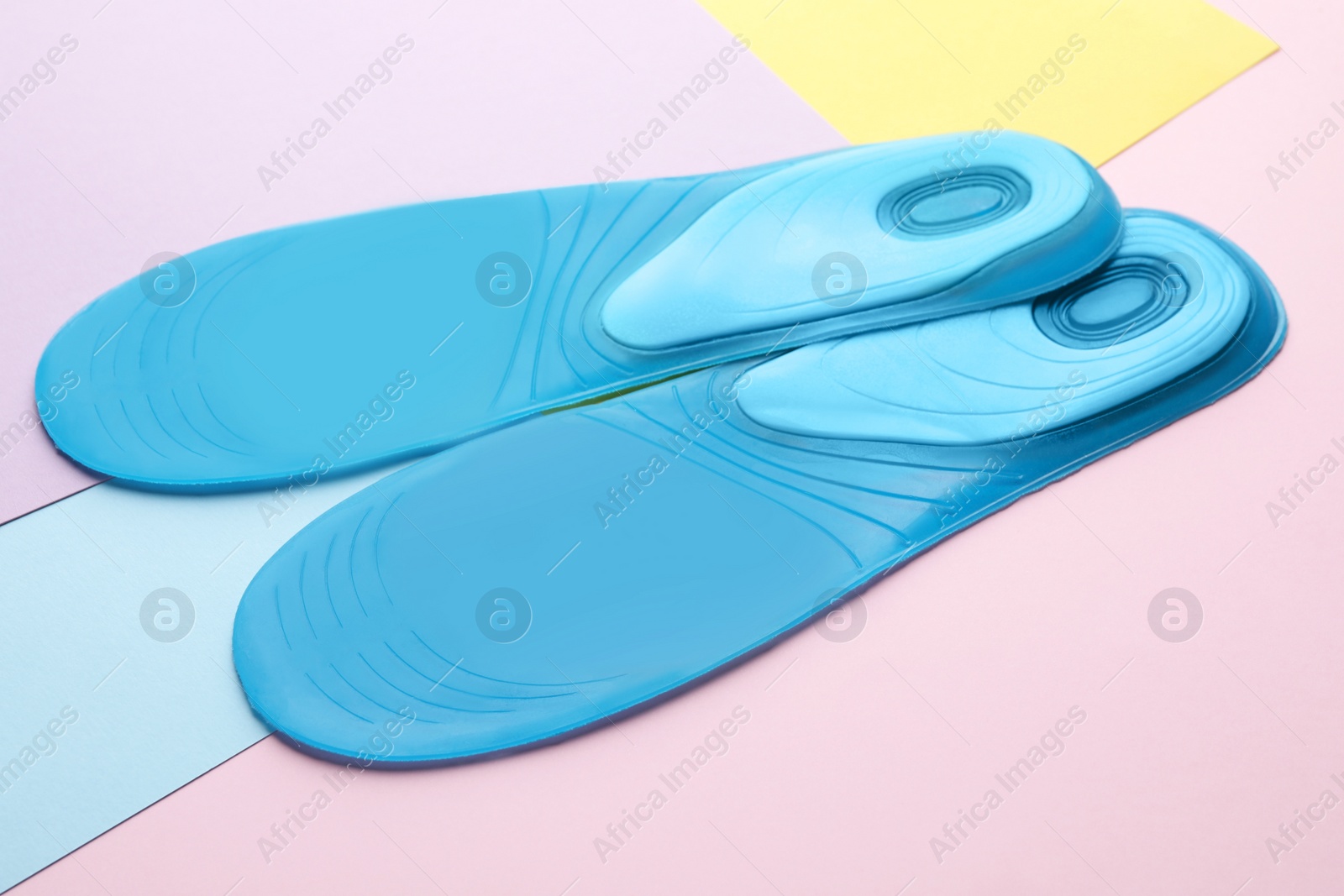 Photo of LIght blue orthopedic insoles on color background