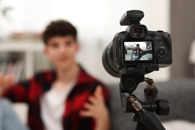 Photo of Teenage blogger explaining something while streaming at home, focus on camera