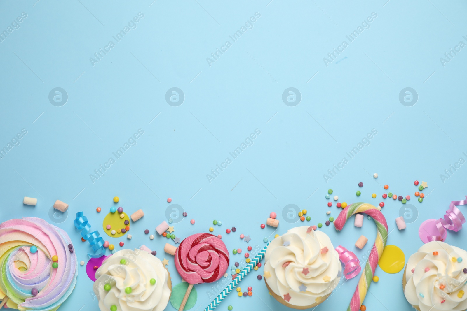 Photo of Flat lay composition with cupcakes on light blue background, space for text. Birthday party