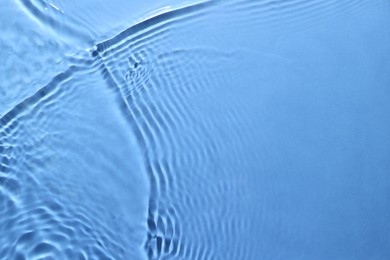 Rippled surface of clear water on light blue background, closeup