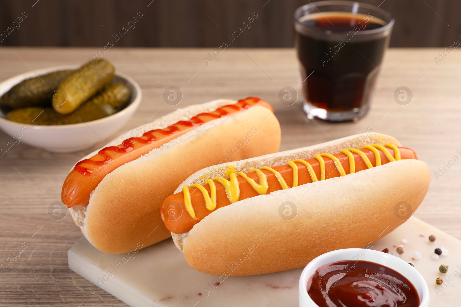 Photo of Tasty hot dogs with mustard and ketchup on wooden table, closeup