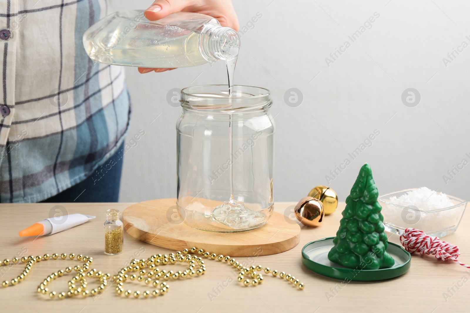 Photo of Woman making beautiful snow globe at wooden table, closeup