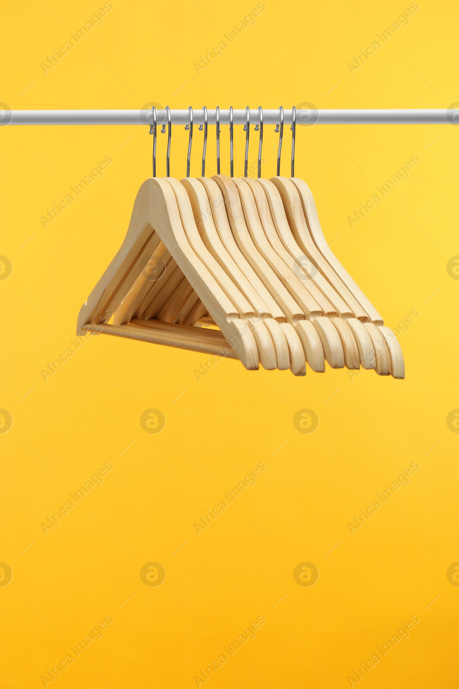 Photo of Empty clothes hangers on rack against orange background