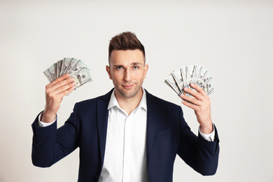 Confident man with cash money on light grey background