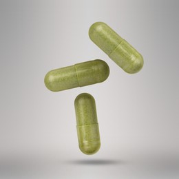 Image of Vitamin. Capsules falling on light grey background