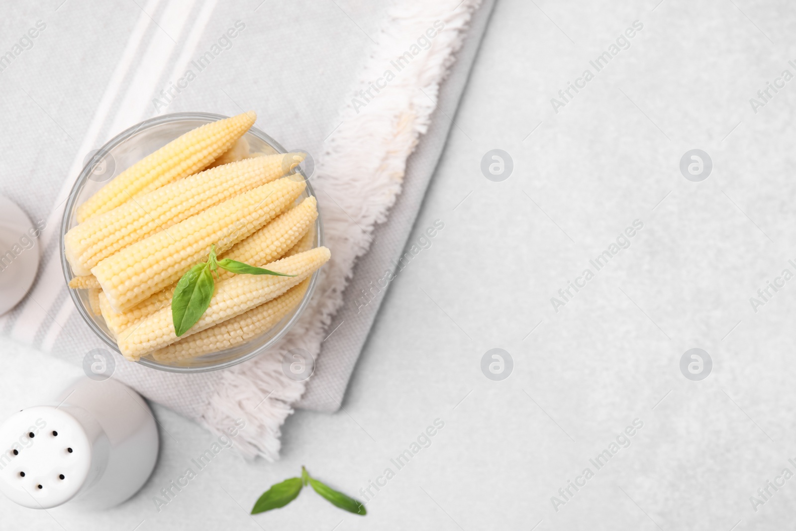 Photo of Canned baby corns with basil on light grey table, flat lay. Space for text