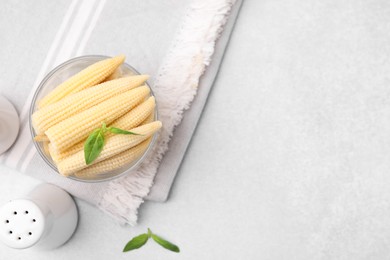 Canned baby corns with basil on light grey table, flat lay. Space for text