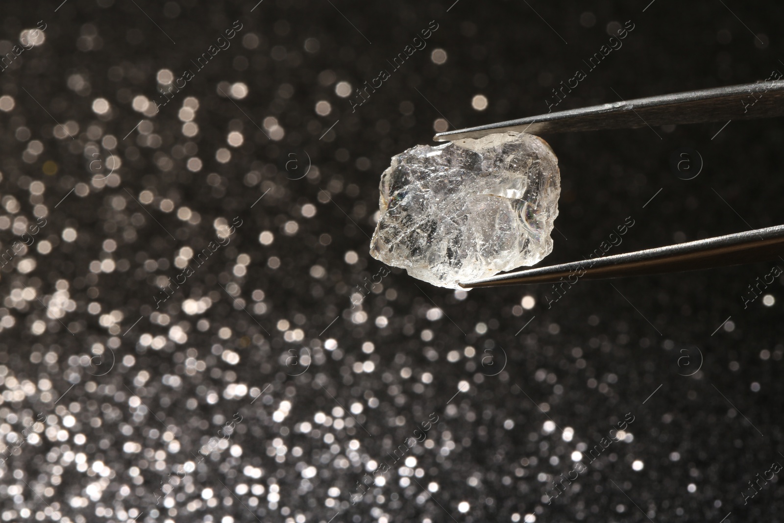 Photo of Tweezers with beautiful diamond on dark shiny background, closeup. Space for text